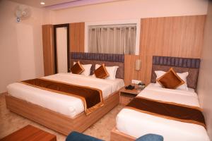 1 dormitorio con 2 camas y 1 silla en Hotel Ekta International, en Deoghar