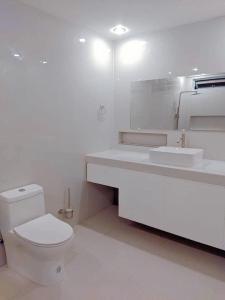 a white bathroom with a toilet and a sink at ABIZA Homestay in Pañge
