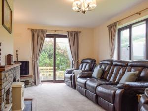 a living room with a leather couch and a fireplace at Coed Tir in Gladestry