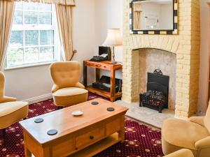 a living room with a fireplace and a table at Tansey Cottage in Hartlebury