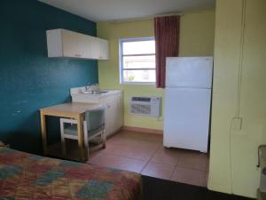 a kitchen with a refrigerator and a table and a sink at Skyway Motel in Daytona Beach