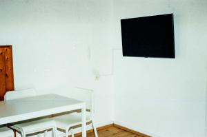 Habitación blanca con mesa y TV en la pared en LIVING SPACE, en Herne