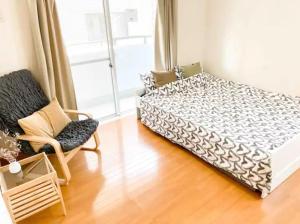 um quarto com uma cama, uma cadeira e uma janela em Urban Core Shikano 501 em Tóquio