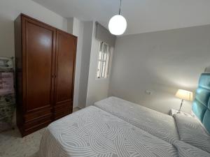 um quarto com uma cama e um armário de madeira em APARTAMENTO AREVALO LUCENA CENTER em Lucena