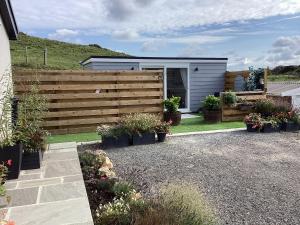 a backyard with a fence and a shed with potted plants at Woodbank Lodge in Amlwch