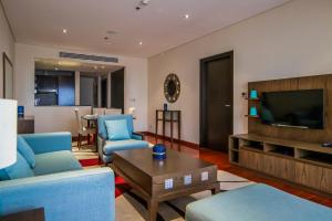 a living room with blue furniture and a flat screen tv at Relaxing 1 bedroom apartment at 5 Star Resort in Dubai