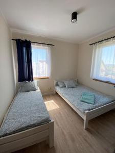 a bedroom with two beds and two windows at Apartamenty Stołowe in Kudowa-Zdrój