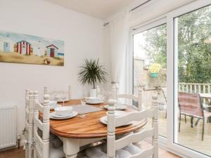 a white dining room with a wooden table and a window at St Botolphs in Hornsea