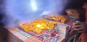 a person cooking food on a grill at Kudil Mud Cottages, Cheemeni in Peringom