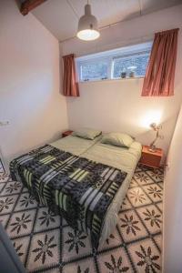 a small bedroom with a bed and a window at 't Pekelhuis - Vakantiehuisje op boerderij Huize Blokland in Hem
