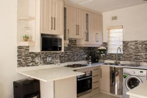 Sandton的住宿－Beautiful 2 bedroom Apartment near Monte Casino，白色的厨房配有水槽和洗碗机