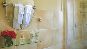 baño con ducha con espejo y rosas rojas en Beautiful 2 bedroom Apartment near Monte Casino en Sandton