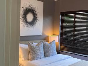 um quarto com uma cama com almofadas e uma janela em Beautiful 2 bedroom Apartment near Monte Casino em Sandton