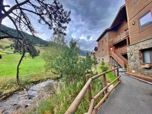 een huis met een houten hek naast een rivier bij Pleta de Peu del Riu hasta 4 personas in Canillo