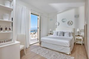 a white bedroom with a bed and a large window at Villa Omikron in Rodia