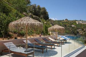 Rodhiá的住宿－Villa Omikron，游泳池旁的一排躺椅和遮阳伞