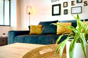 a living room with a blue couch and a table at Le Loft - Bain jacuzzi et Sauna in Nîmes