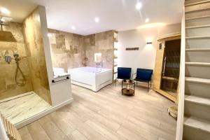 a bathroom with a tub and a shower and a sink and a toilet at Le Loft - Bain jacuzzi et Sauna in Nîmes