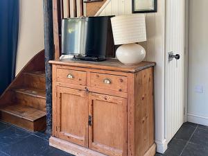 a tv on top of a wooden dresser with a lamp at Southfield Art Studio in Braunston