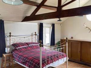 1 dormitorio con 1 cama con manta de cuadros roja en Southfield Art Studio, en Braunston