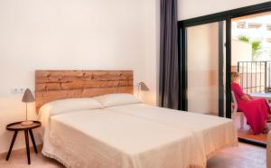 a woman sitting in a chair in a bedroom with a bed at Ona Hacienda del Álamo Golf Apartments in Fuente Alamo