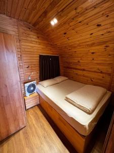 una piccola camera da letto con un letto in una camera in legno di The Hobbit Bungalow a Da Lat