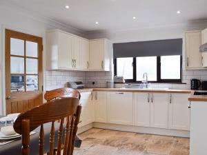 a kitchen with white cabinets and a table and a window at Pant Yr Awel in Llanycrwys