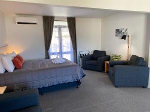 ein Schlafzimmer mit einem Bett, einem Sofa und einem Stuhl in der Unterkunft The Bealey Hotel in Arthur's Pass