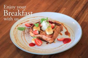 a plate with a piece of toast with strawberries and whipped cream at Grandmas Plus Hotel Seminyak in Seminyak