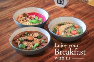 three bowls of food sitting on a wooden table at Grandmas Plus Hotel Seminyak in Seminyak