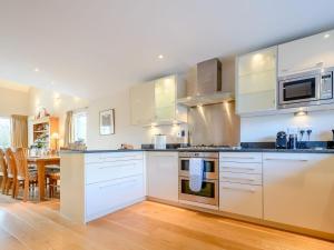a kitchen with white cabinets and a dining room at Honey Cottage in Somerford Keynes