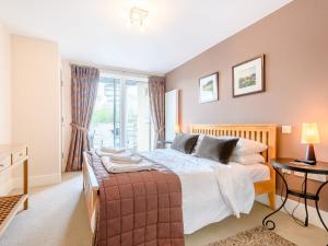 a bedroom with a large bed and a window at Honey Cottage in Somerford Keynes