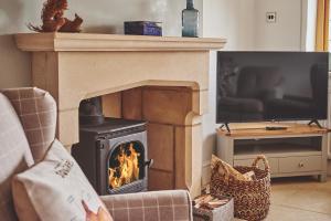 a person sitting in a chair in front of a fireplace at Squirrel Barn in Moreton in Marsh