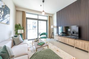 uma sala de estar com uma grande televisão de ecrã plano em Stunning 1BR Apt high floor with palm view & private beach at EMAAR Beachfront em Dubai