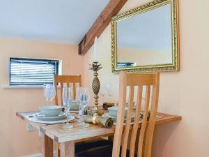 a dining room table with glasses and a mirror at Pilgrims Barn in Hitcham