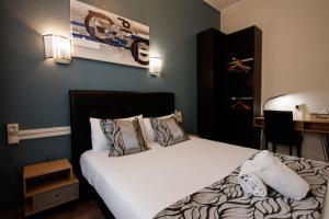 a bedroom with a bed with white sheets and pillows at Hotel Astoria in Carcassonne