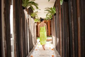 a woman walking down a hallway in a green dress at Grandmas Plus Hotel Seminyak in Seminyak