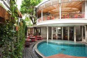 a house with a swimming pool in front of a building at Grandmas Plus Hotel Seminyak in Seminyak