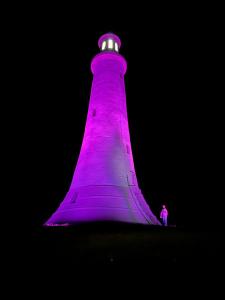 un phare violet avec une personne debout devant lui dans l'établissement Log home village, à Ulverston
