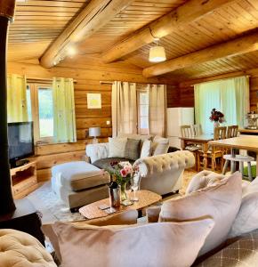 una sala de estar con muebles blancos y techo de madera. en Log home village, en Ulverston