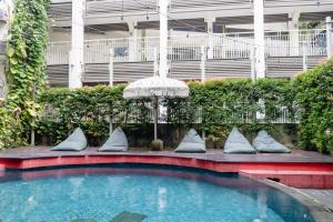 a small swimming pool with pillows and an umbrella at Grandmas Plus Hotel Seminyak in Seminyak