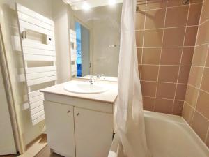 a bathroom with a sink and a tub and a mirror at Le Flocon, T2, vue montagne, parking gratuit, 4 personnes in Luchon