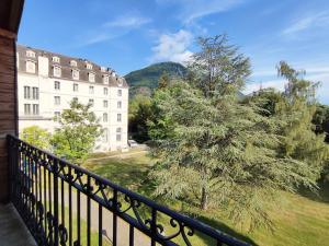 einen Balkon mit Blick auf ein Gebäude und einen Baum in der Unterkunft Le Flocon, T2, vue montagne, parking gratuit, 4 personnes in Luchon