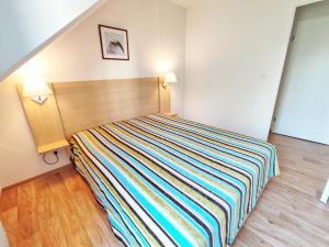 a bedroom with a bed with a colorful striped blanket at Le Flocon, T2, vue montagne, parking gratuit, 4 personnes in Luchon