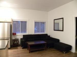 a living room with a black couch and a refrigerator at Fireweed Motel in Smithers