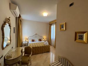una camera da letto con un letto, un tavolo e uno specchio di Angeles Inn a Venezia