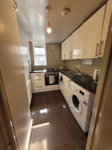 een keuken met een wasmachine en een wastafel bij 43 Kimberly road apartment in Londen