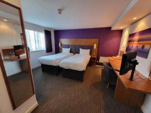 a hotel room with two beds and a television at Tyger Inn Derby in Derby