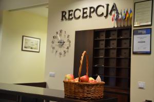 a basket of apples sitting on a counter with a clock at Hotel Aviator Kielce in Kielce