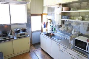 a kitchen with white cabinets and a sink and a microwave at FUJI新倉山 in Azagawa
